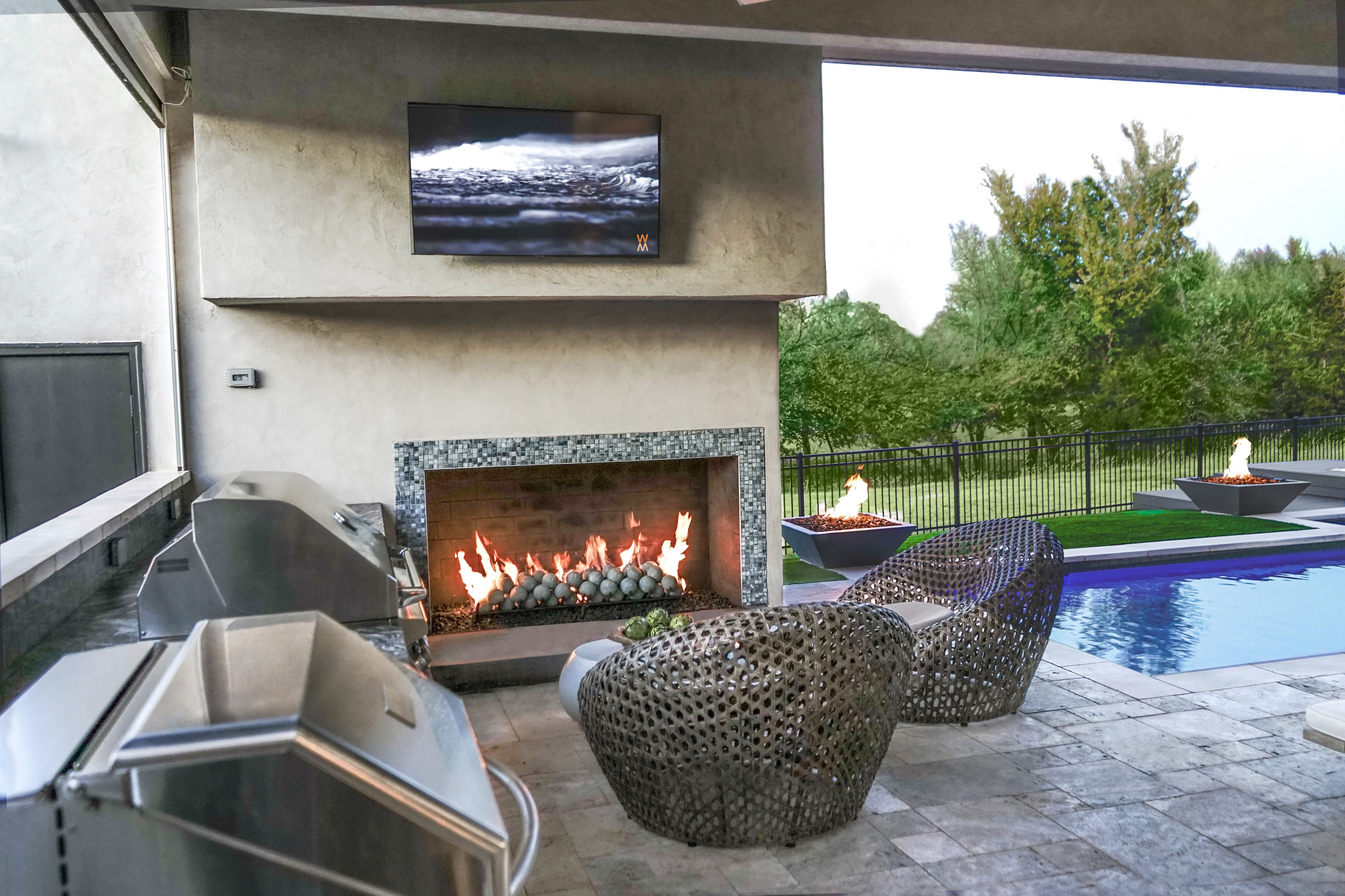 Outdoor kitchen, fireplace and pool by Studio W
