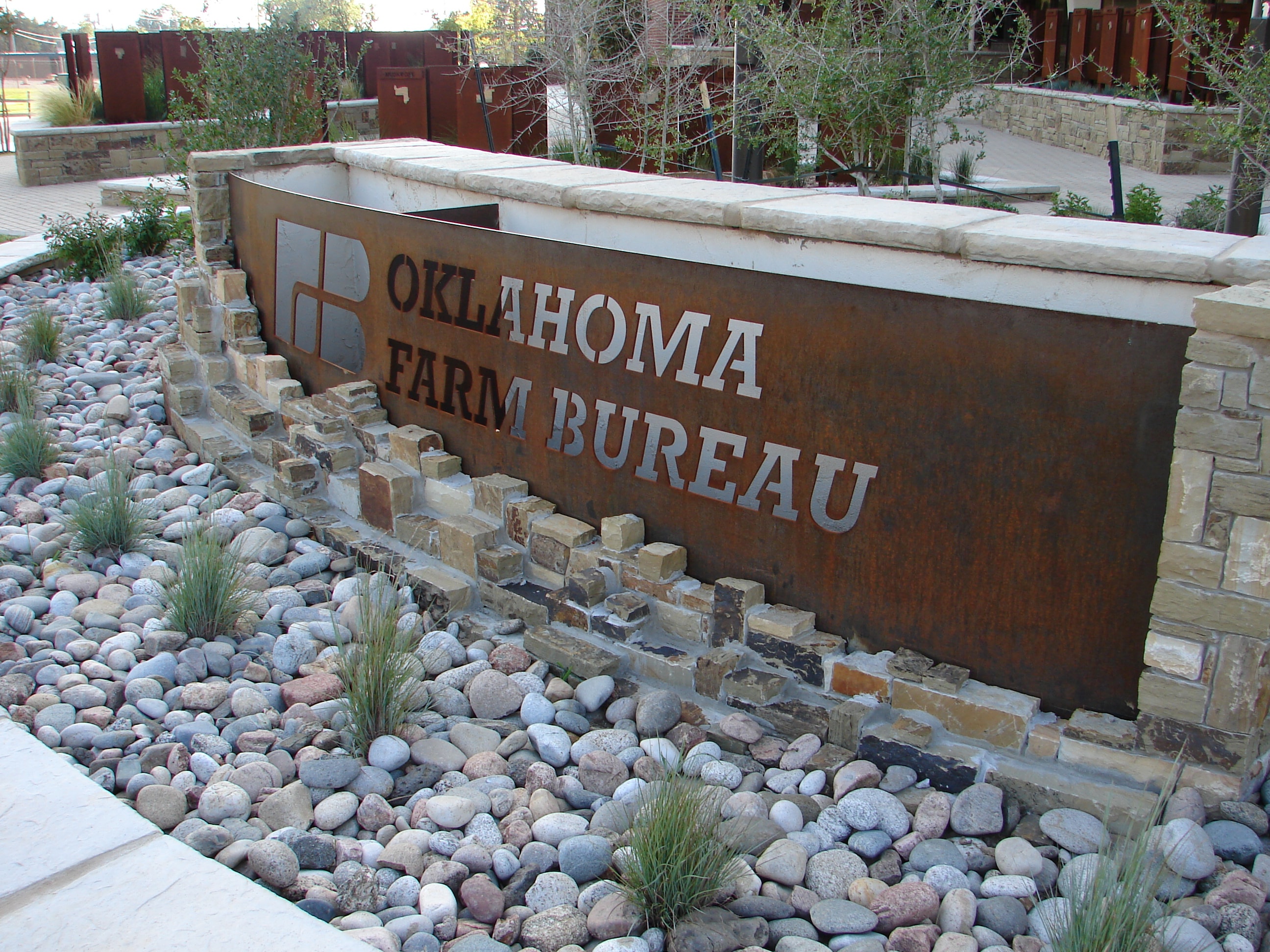 Oklahoma Farm Bureau corten steel monument sign with river rock landscaping