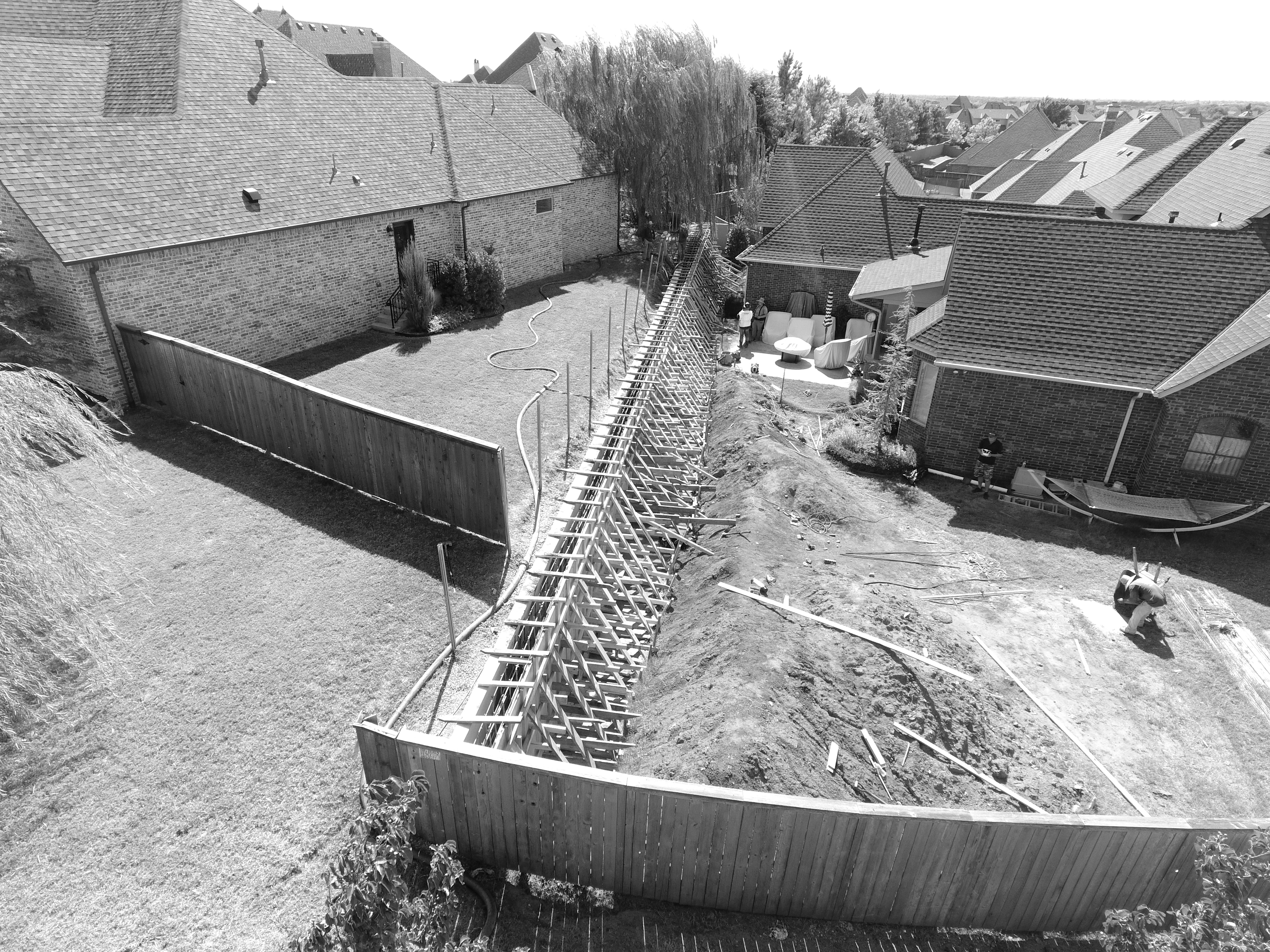 Black and white aerial view of retaining wall formwork under construction between residential properties