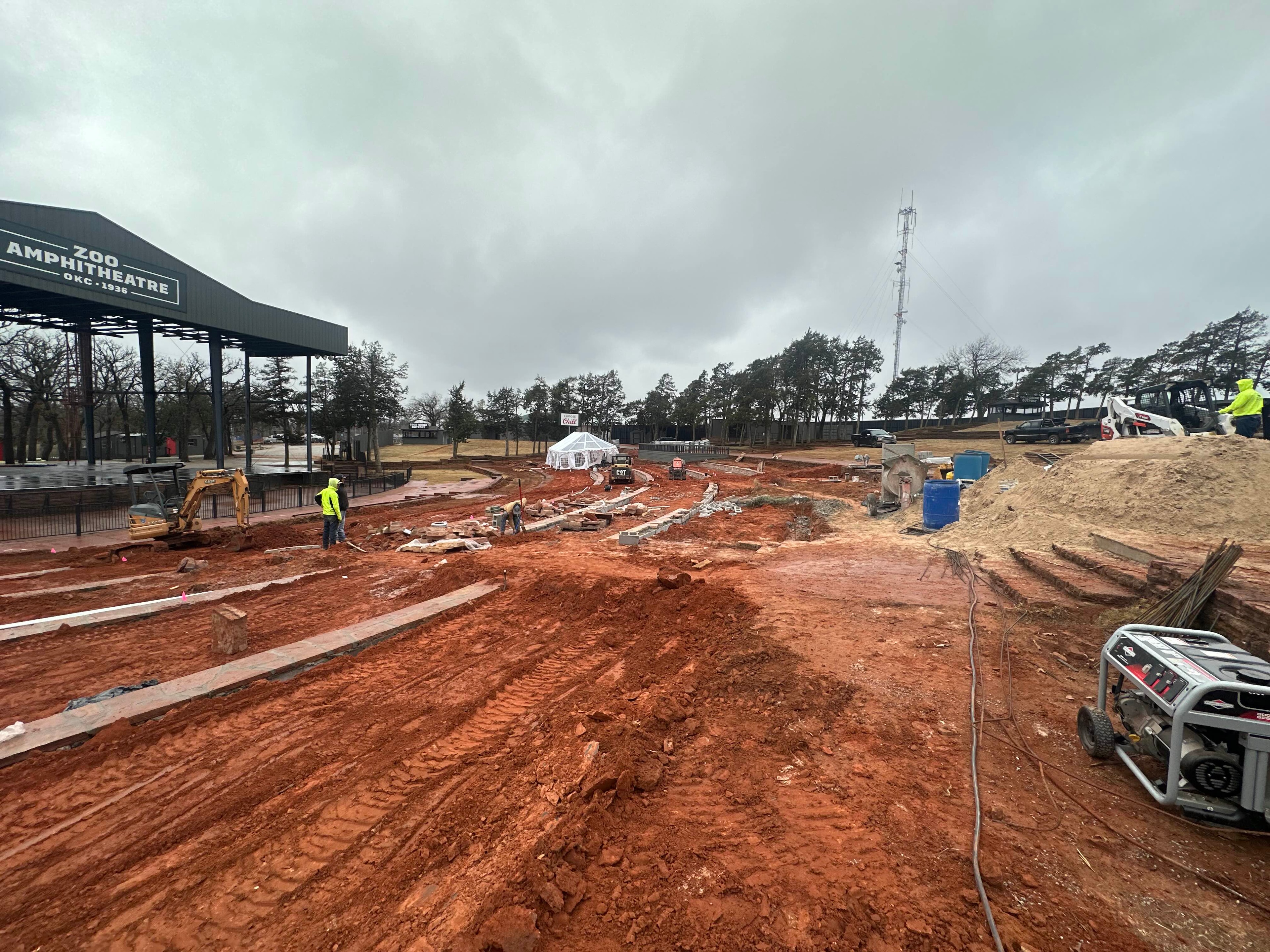 OKC Zoo Amphitheatre excavation and retaining wall installation with equipment and crew in rain