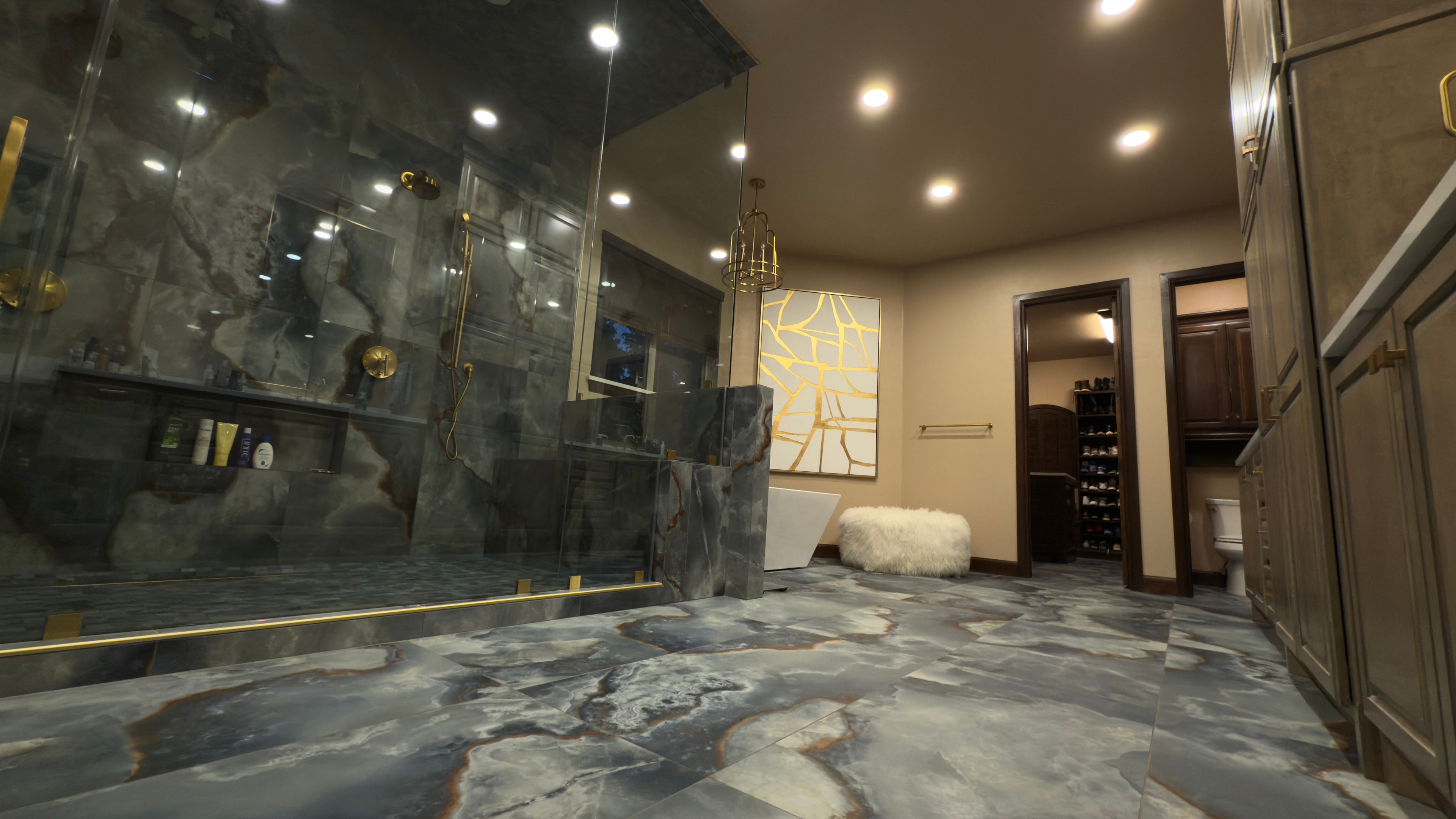Luxury master bath with dramatic marble tile, gold fixtures, and walk-in glass shower
