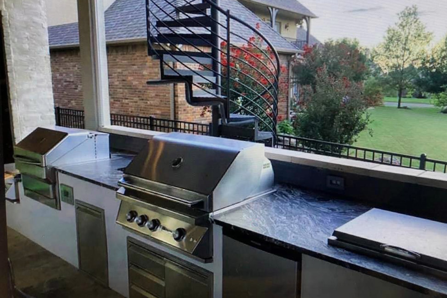 Outdoor kitchen with spiral staircase and granite countertops