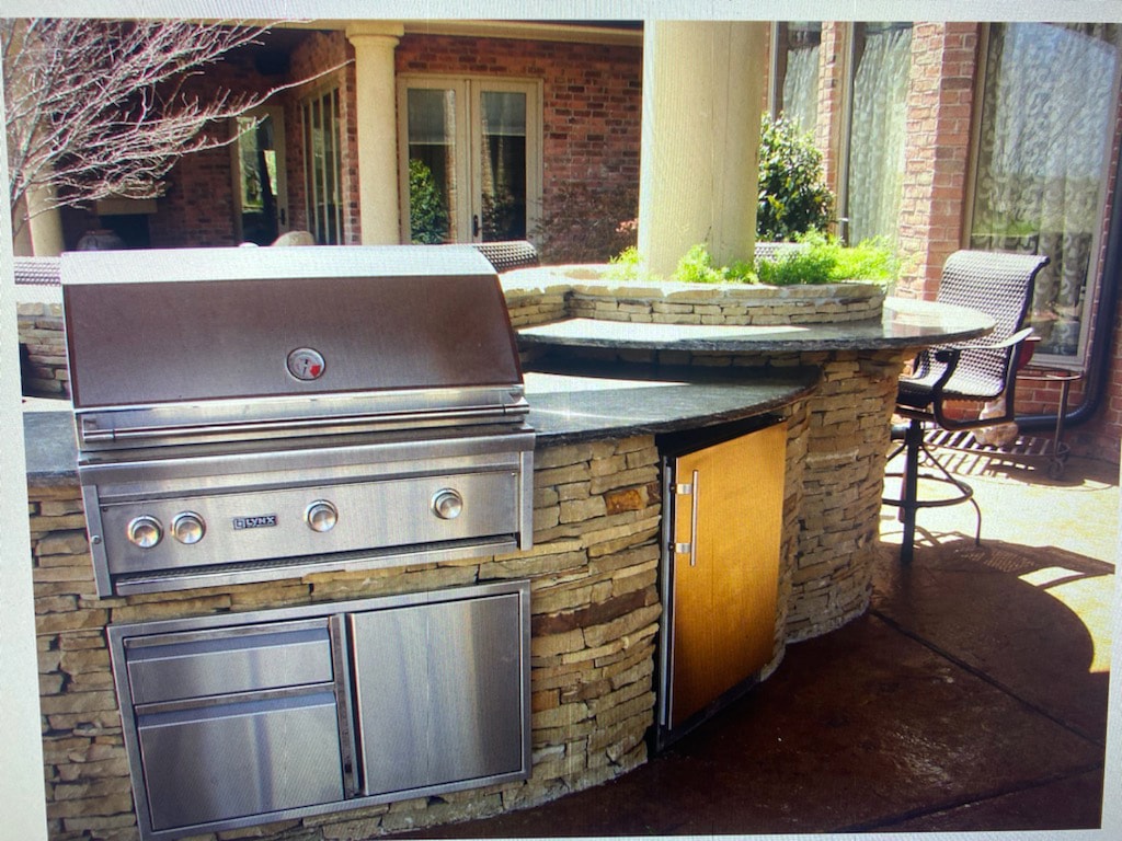 Stone outdoor kitchen with built-in Lynx grill and bar seating